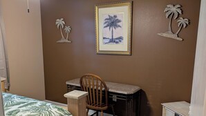 Un dormitorio con cama, escritorio, silla y mesita de noche.