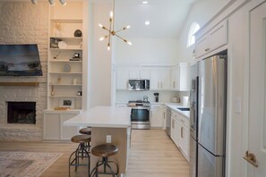 Een moderne keuken met witte kasten, roestvrijstalen apparatuur en een centraal eiland met barkrukken.