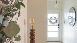 A hallway with a wooden floor, a black console table with a lamp, a mirror, and a plant. - Cozy 3BR/2BA - Peaceful, Pet-friendly Home (Cedar Park)