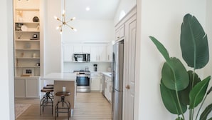 A modern kitchen with white cabinetry, a stainless steel refrigerator, and a wooden floor. - Cozy 3BR/2BA - Peaceful, Pet-friendly Home (Cedar Park)