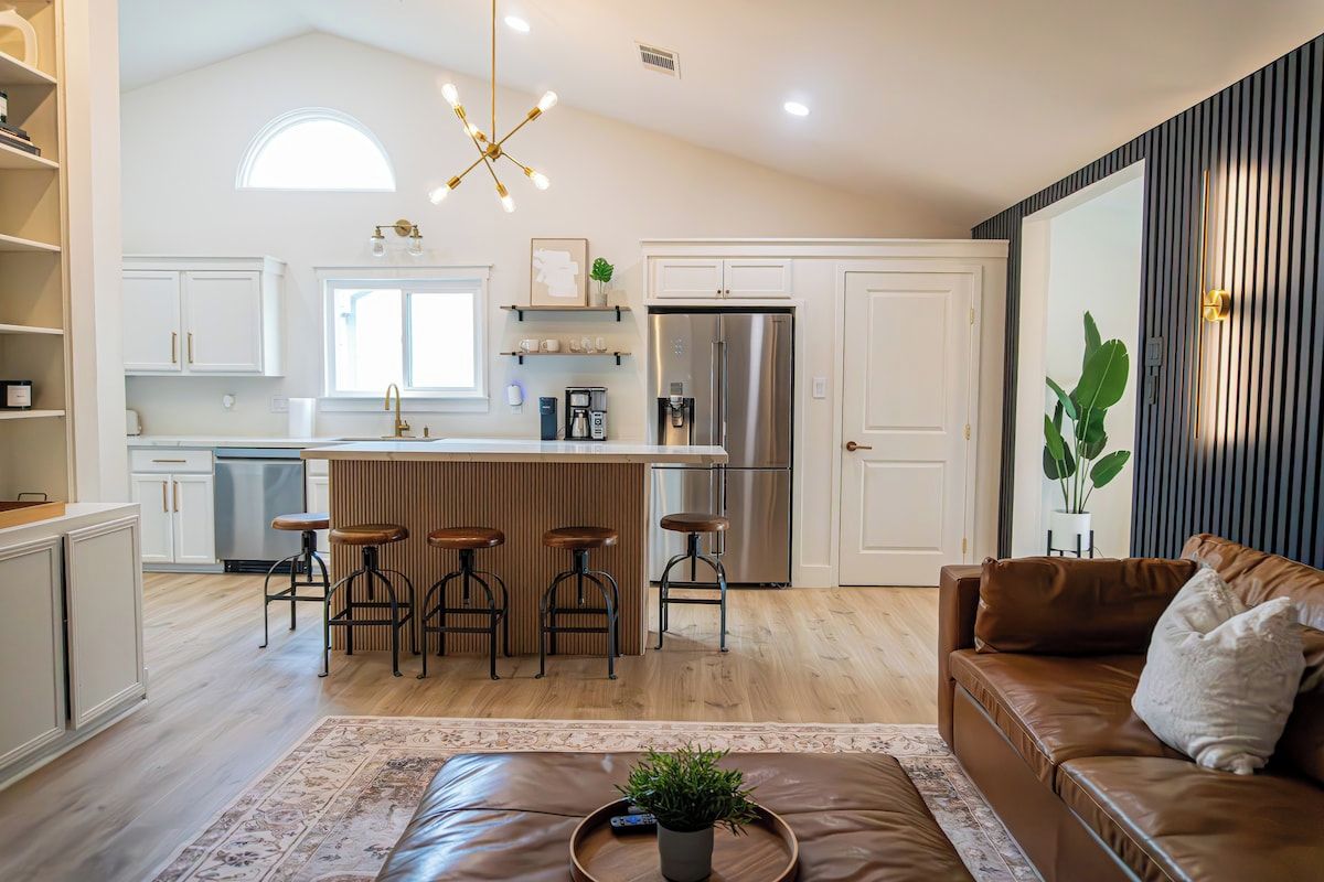 A modern kitchen with a central island, bar stools, and a refrigerator.