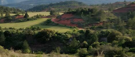 Vista panorámica de un paisaje montañoso con un campo de golf, montañas al lejano y cielo despejado.