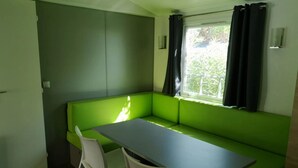 Una habitación con un sofá verde, una mesa y dos sillas.