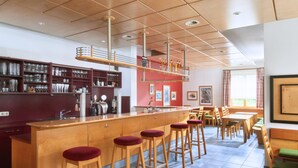 Een bar met krukken, een toonbank en planken met glazen en flessen.