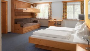Een kamer met een stapelbed, een slaapbank, een bureau en een televisie.