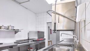 Een RVS professionele keuken met een inbouwoven, een spoelbak en een afzuigkap.