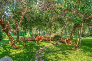 A garden with trees, a stone pathway, and a green fence.