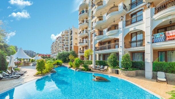 A hotel with a swimming pool, multiple balconies, and lush greenery. - Sunny Beach resort apartment with sunny balcony, pools & spa near beach (Sunny Beach)