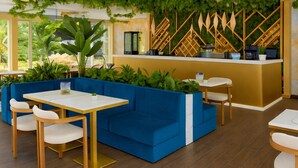 A restaurant with blue seating, a counter, and a green wall with plants. - Sunny Beach resort apartment with sunny balcony, pools & spa near beach (Sunny Beach)