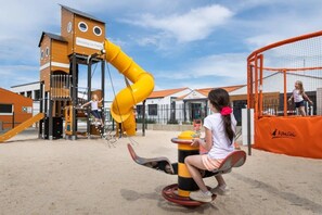 Ein Spielplatz mit Rutsche, Klettergerüsten und einer Wippe.