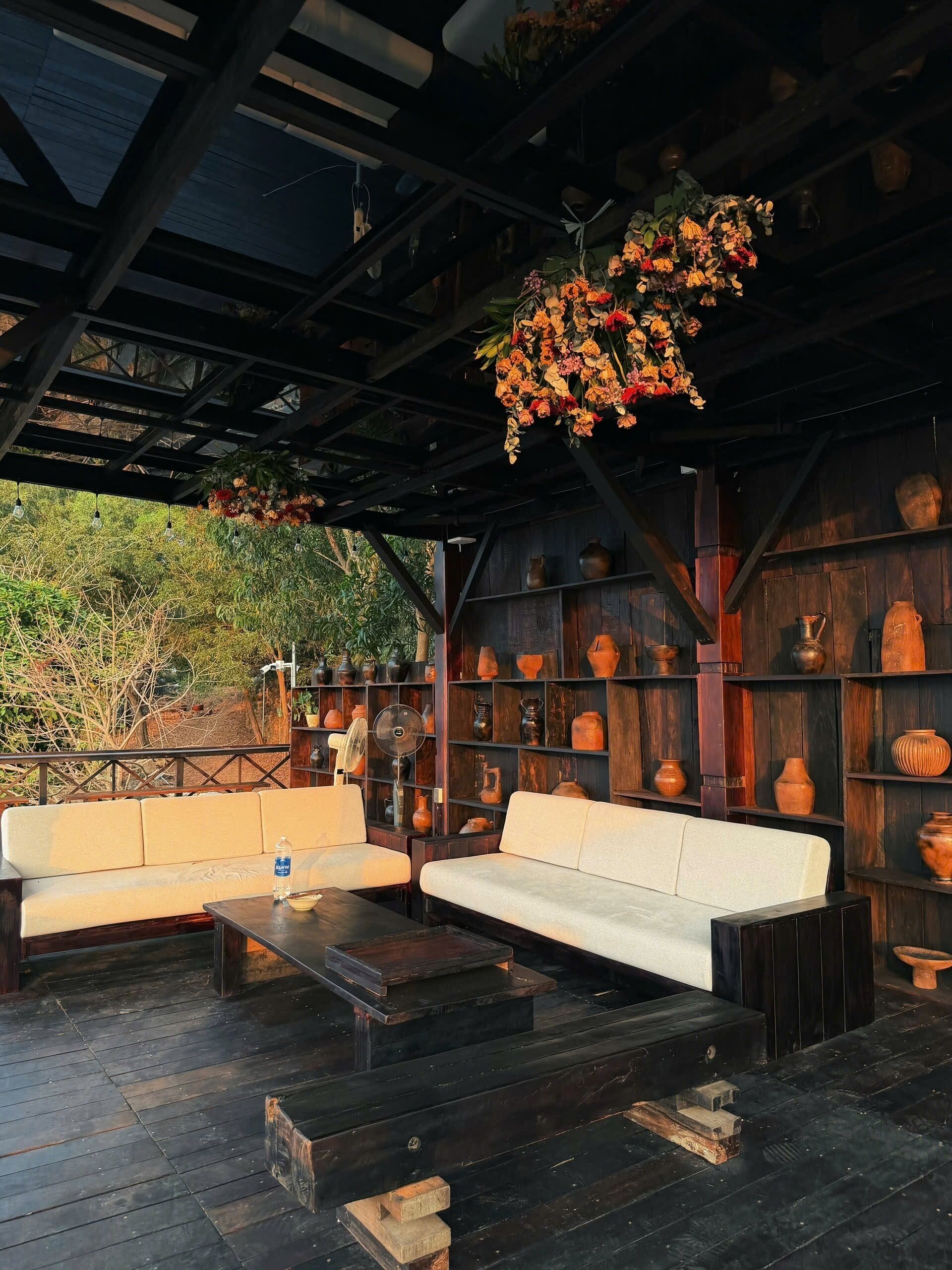 An outdoor seating area with sofas and a table, surrounded by shelves with pottery.