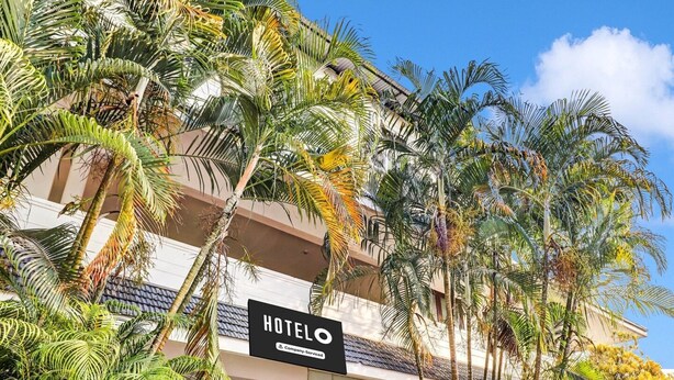 Ein Hotelgebäude mit einem Schild, auf dem 'HOTELO' steht, und einem Firmenlogo.