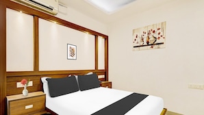 Ein Hotelzimmer mit Bett, Nachttischen, Klimaanlage, Wandkunst und einem gerahmten Bild.