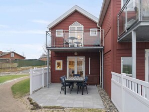 A two-story house with a balcony, a patio with a table and chairs, and a fenced yard. - 4 Star Holiday Home in Hadsund (Lokken)