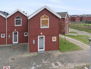 Eine Reihe roter Gebäude mit weißen Verzierungen, nummerierten Türen und kleinen Fenstern.