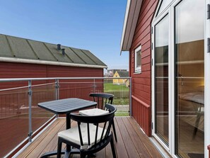 A deck with a table and chairs, a sliding glass door, and a view of a building in the background. - 4 Star Holiday Home in Hadsund (Lokken)