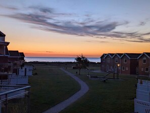 A coastal view with a pathway leading to a row of brick buildings, a grassy area, and the ocean in the background. - 4 Star Holiday Home in Hadsund (Lokken)
