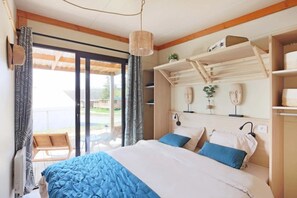 A bedroom with a bed, a hanging light fixture, a window with curtains, and a view of the outside. - Chalet 3 étoiles - ccbfgge (Lépin-le-Lac)