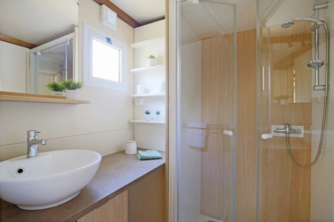 Une salle de bain avec un lavabo blanc, une cabine de douche en verre et des meubles en bois.