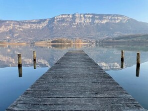 A wooden pier extending into calm water with a mountain in the background. - Camping 3 étoiles - ccbfgh0 (Lépin-le-Lac)