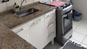 Eine Küche mit Granit Arbeitsplatte, weißen Schränken, einem Einbauofen, einer Mikrowelle, einem Mixer, einem Spülbecken und einem Wischmopp.