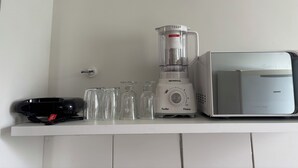 Eine Küchenarbeitsplatte mit einem weißen Mixer, einer Mikrowelle und mehreren Gläsern.
