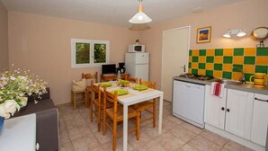 Una cocina compacta con una mesa de comedor, sillas, un refrigerador, un microondas, un fregadero y un salpicadero de azulejos.