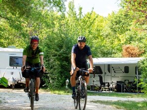 Zwei Radfahrer auf einem Schotterweg, im Hintergrund Wohnmobile.