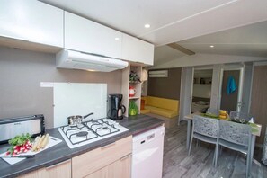 A compact kitchen with a gas stove, a coffee maker, and a dishwasher. - Camping 4 étoiles - Piscine  - ccbehhf (Saignon)