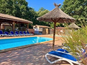 A swimming pool with lounge chairs and thatched umbrellas.