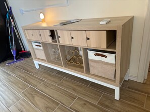 A wooden cabinet with multiple drawers and storage compartments, a mop, and a broom on the floor. - Cozy 1-bedroom bungalow in historic downtown Mission with private Parking (Mission)