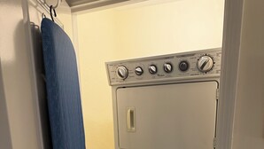 Un appareil compact combinant lave-linge et sèche-linge, doté d’un panneau de commande, d’une poignée de porte et d’une serviette bleue accrochée à la porte.