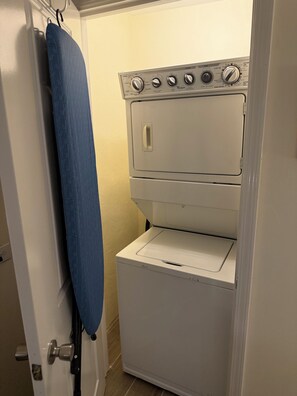Eine kompakte Waschmaschine und Trockner Kombination mit Bedienfeld, Türgriff und einem blauen Handtuch an der Tür.