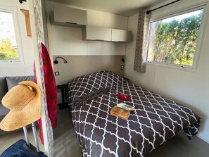 Ein gemütlicher Raum mit Bett, einer kleinen Sitzecke, einem Fenster mit Blick und einem Deckenventilator.