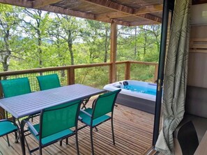 A covered outdoor area with a table and chairs, a hot tub, and a view of trees. - Camping 4 étoiles - Piscine  - ccbehib (Saignon)