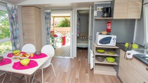 Una cocina compacta con microondas, cafetera y estantes para guardar cosas.