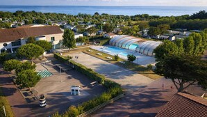 A residential area with a large swimming pool, houses, and a view of the sea. - Camping 3 étoiles - Piscine  - ccbffbc (Saint-Denis-d'Oléron)