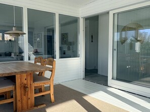 A dining area with a wooden table and chairs, large windows, and a view of the interior. - 4 Star Holiday Home in Middelfart (Middelfart)