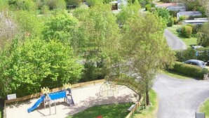 Een landelijk landschap met een speeltuin, huizen en velden.
