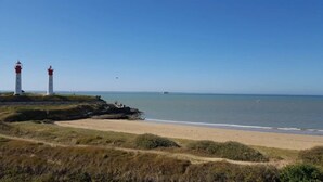 Een kustlandschap met twee vuurtorens, een zandstrand en een heldere lucht.