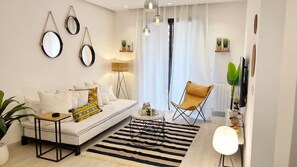 A modern living room with a sofa, coffee table, and a chair. There are wall-mounted mirrors, a floor lamp, and a striped rug. - Paradise Home - Appartement Moderne à La Marsa (La Marsa)
