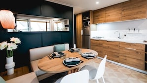 Een moderne keuken met houten kastjes, een witte aanrecht en een eethoek met een ronde tafel en stoelen.
