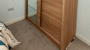 A bedroom with a wooden wardrobe, a mirror, and a light fixture. - Nay Apartment Two-Bedroom Appt in Coventry (Longford)