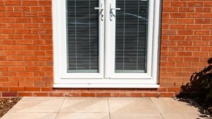 A double door with a white frame and a vented glass panel, set in a brick wall. - Nay Apartment Two-Bedroom Appt in Coventry (Longford)