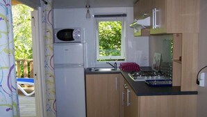A compact kitchen with a microwave, stove, and sink. - Camping 3 étoiles - Piscine  - ccbffec (Arces)