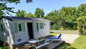 Una casa móvil pequeña con un patio, una mesa y una silla de descanso.