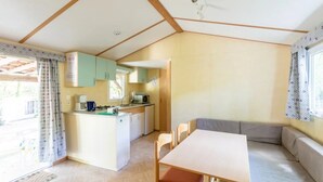 Una cocina compacta con una isla central, un comedor con mesa y sillas, y una ventana con cortinas.