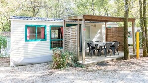 A small cabin with a patio, a table, and chairs. - Camping 3 étoiles - Piscine  - ccbfg0g (Chauffour-sur-Vell)