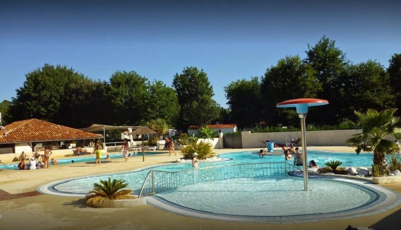 A swimming pool area with a water slide, lounge chairs, and a covered seating area.