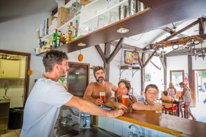 Eine Bar mit einer Theke, Regalen voller Flaschen und einem Fernseher.